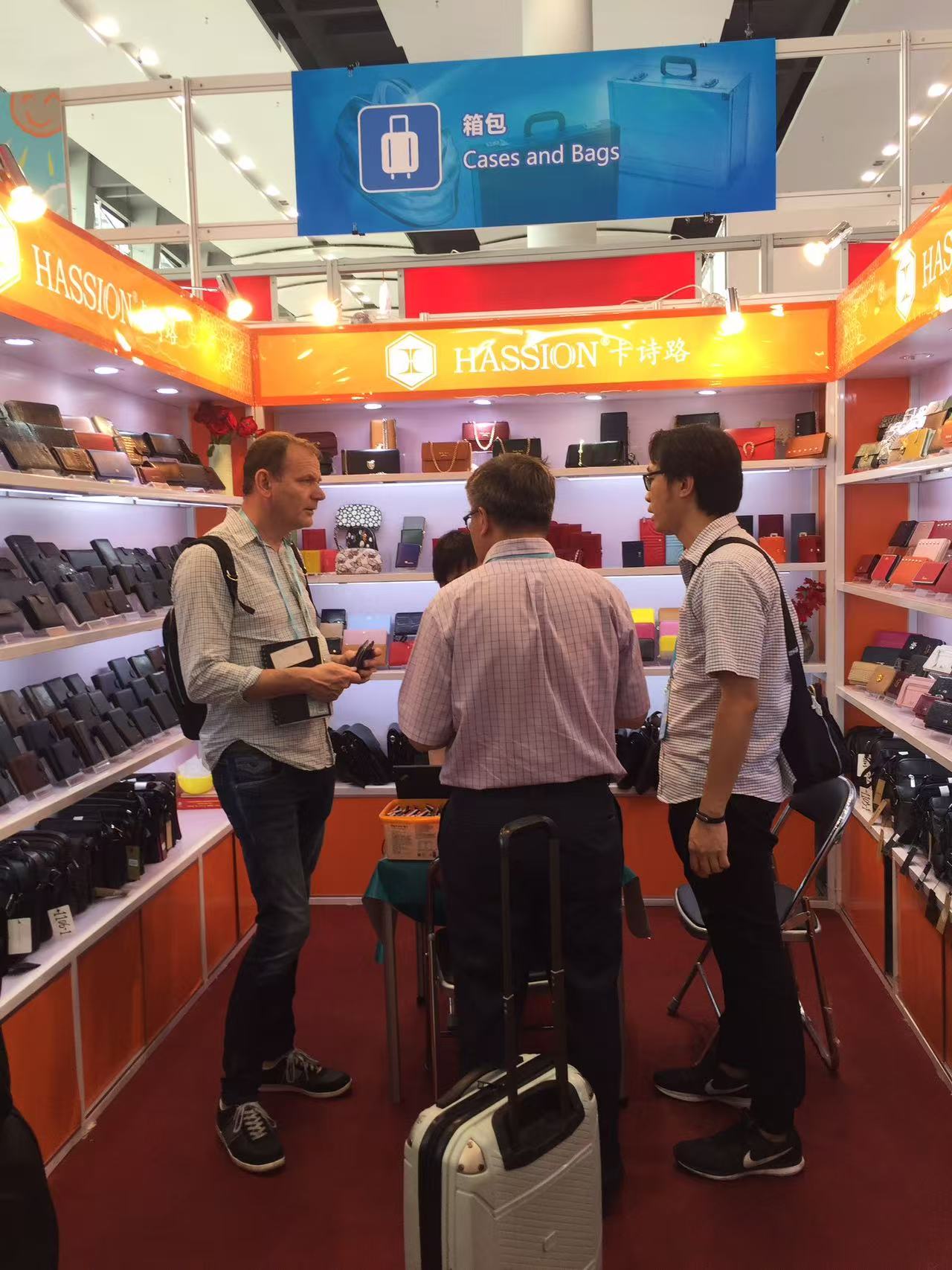 Trade show discussion with overseas buyers reviewing leather goods samples